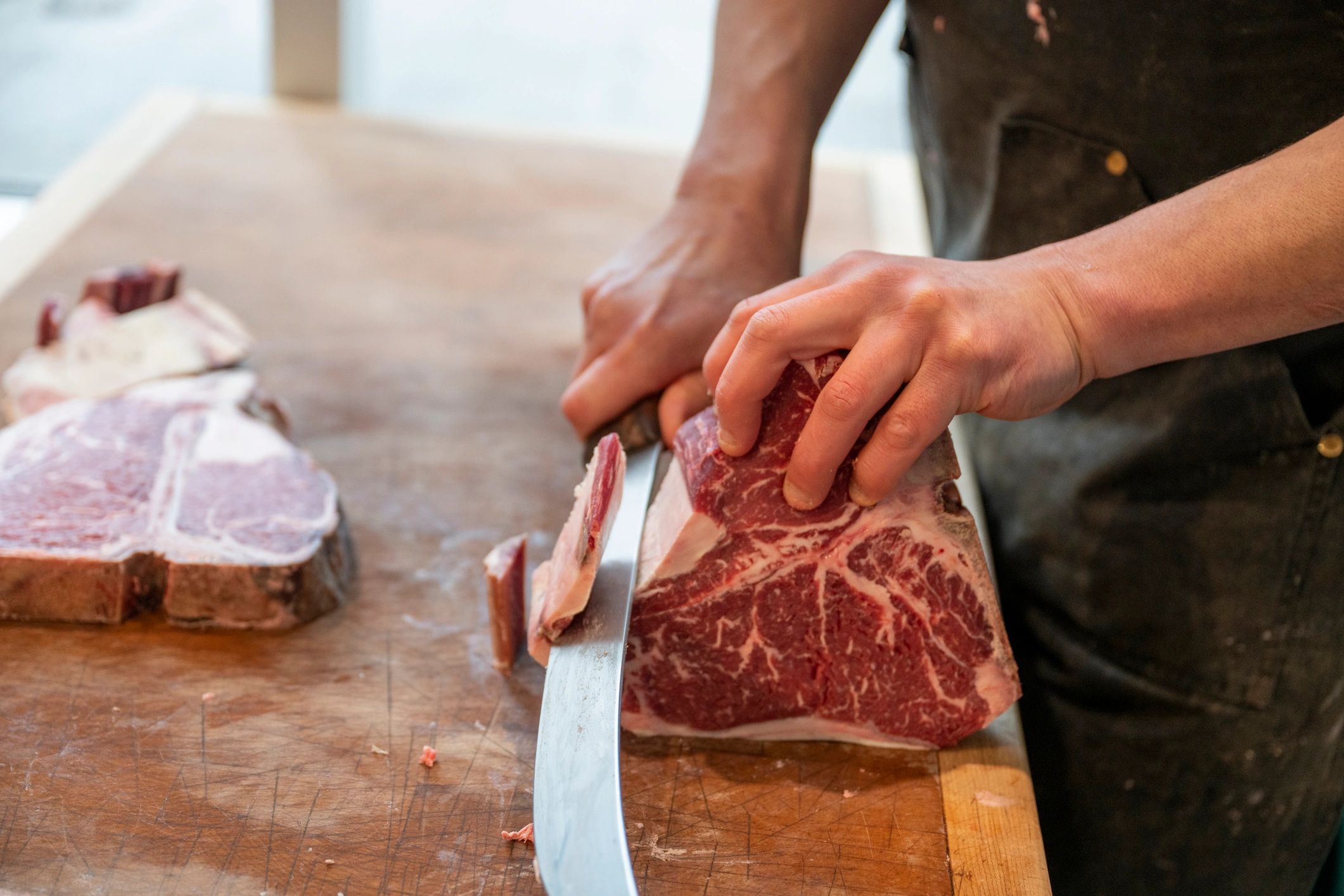 Butcher slicing raw beef